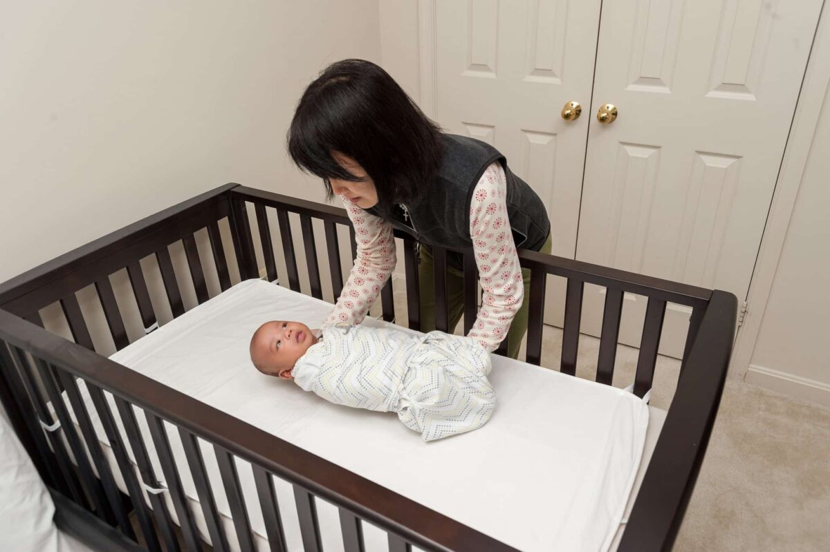 Mother putting baby into cot.