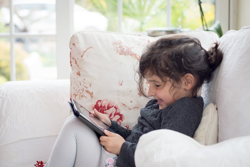 A child using an online device to learn from their home.