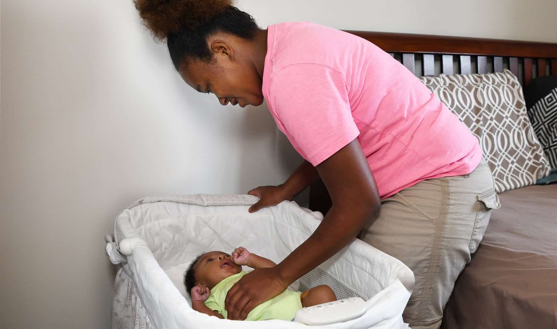 New mother tending to baby in cot.
