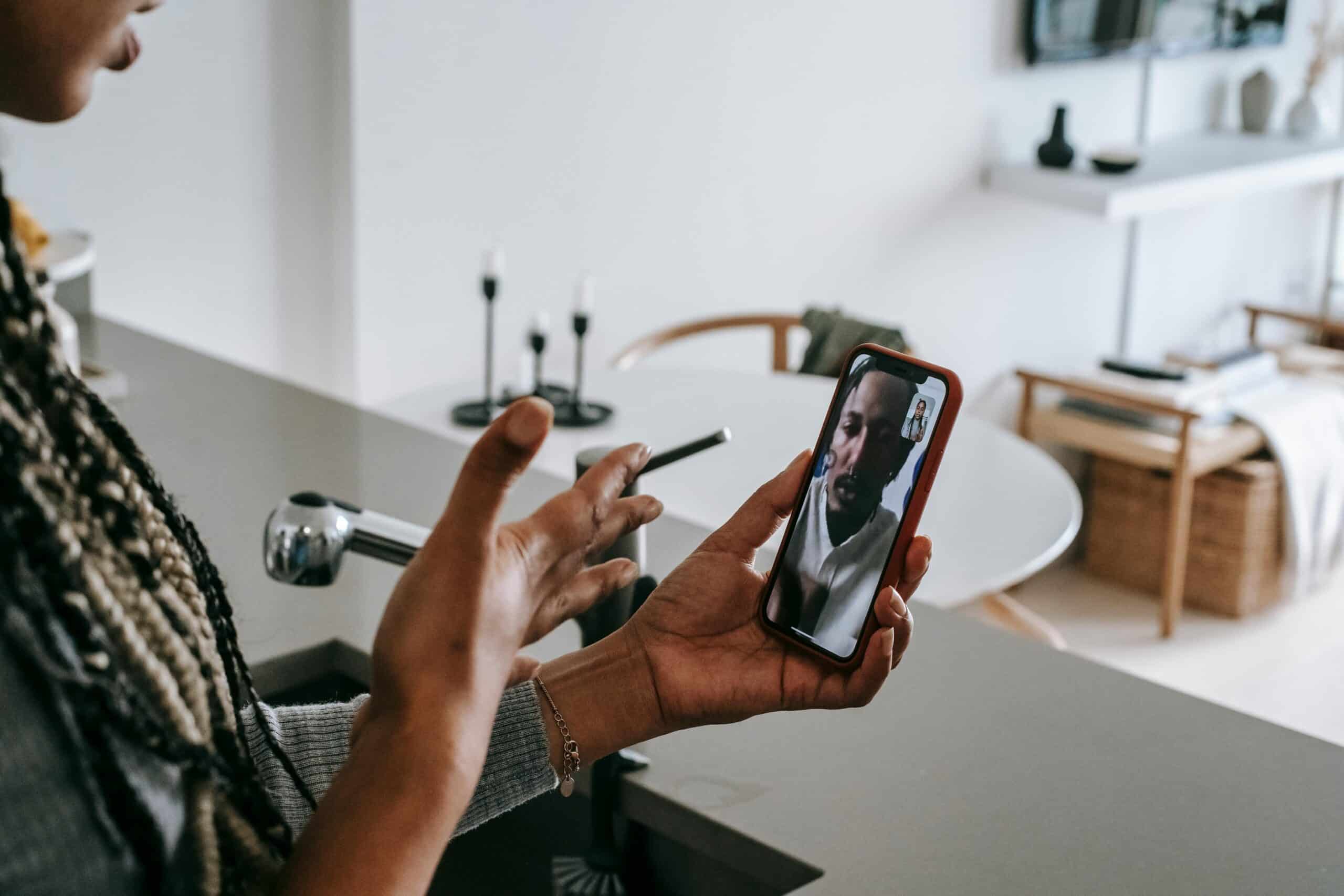 A woman is speaking with her teenage son over a video call, the son looks visually upset.