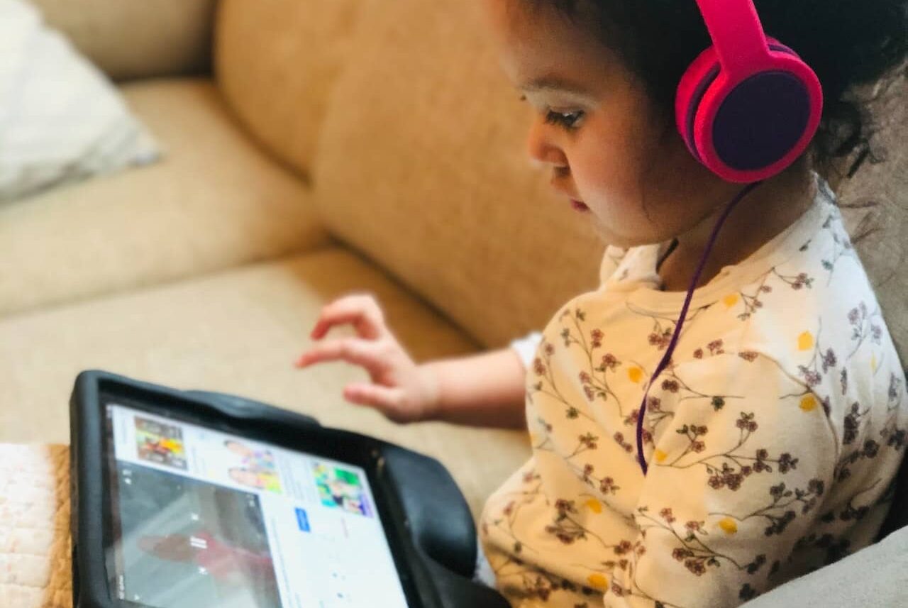 Child sitting on sofa using ipad.