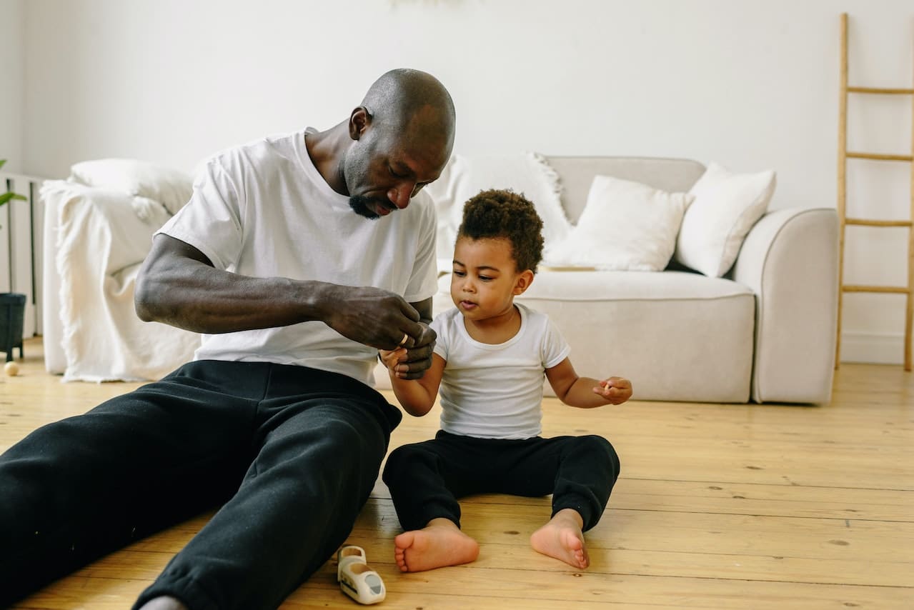 Son sat on the floor with father.