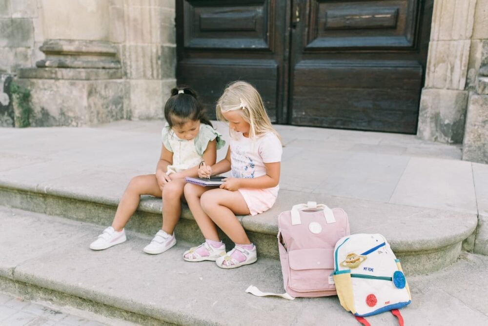 Two young girls sitting on stairs outside.
