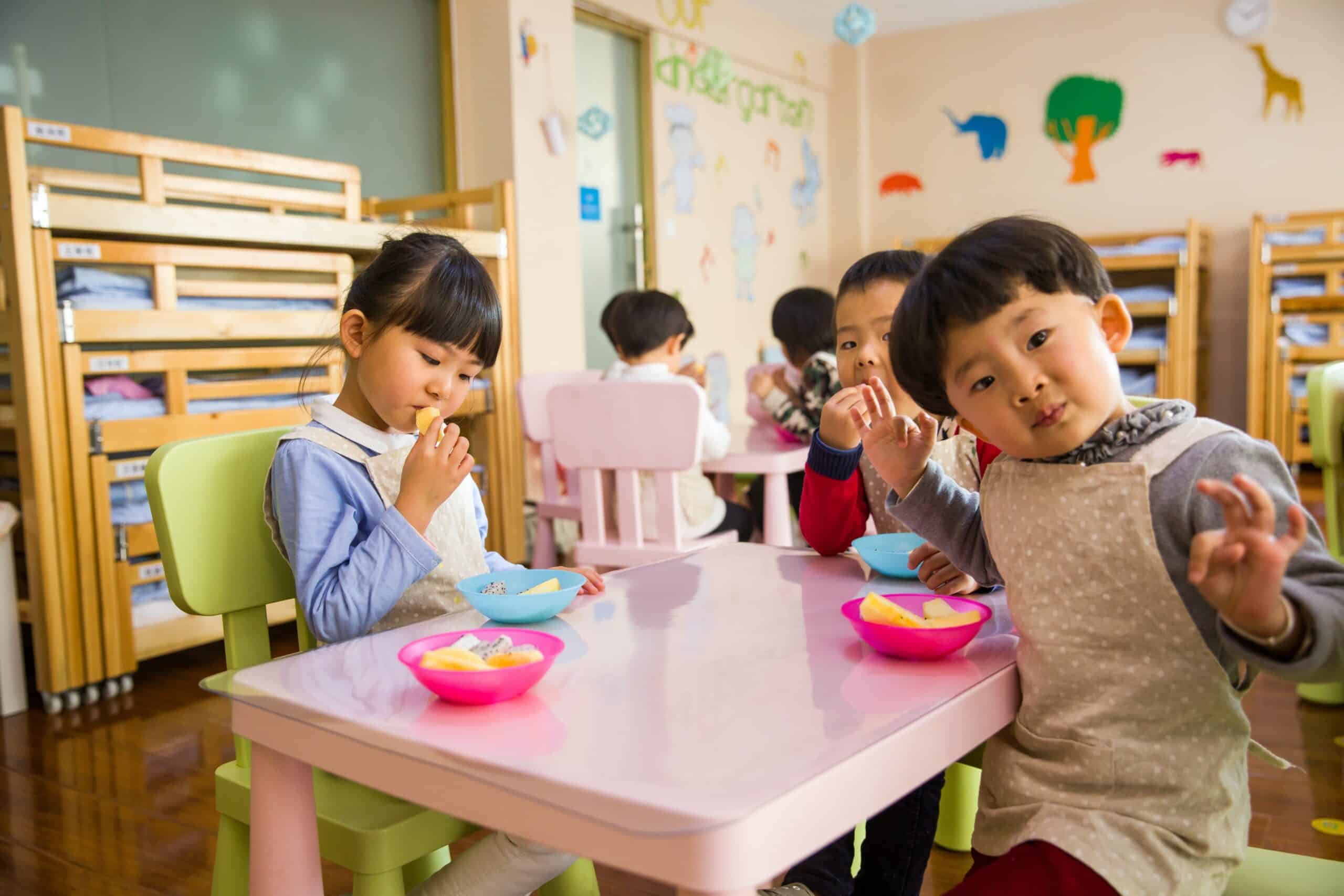 Preschool children eat fruit together.