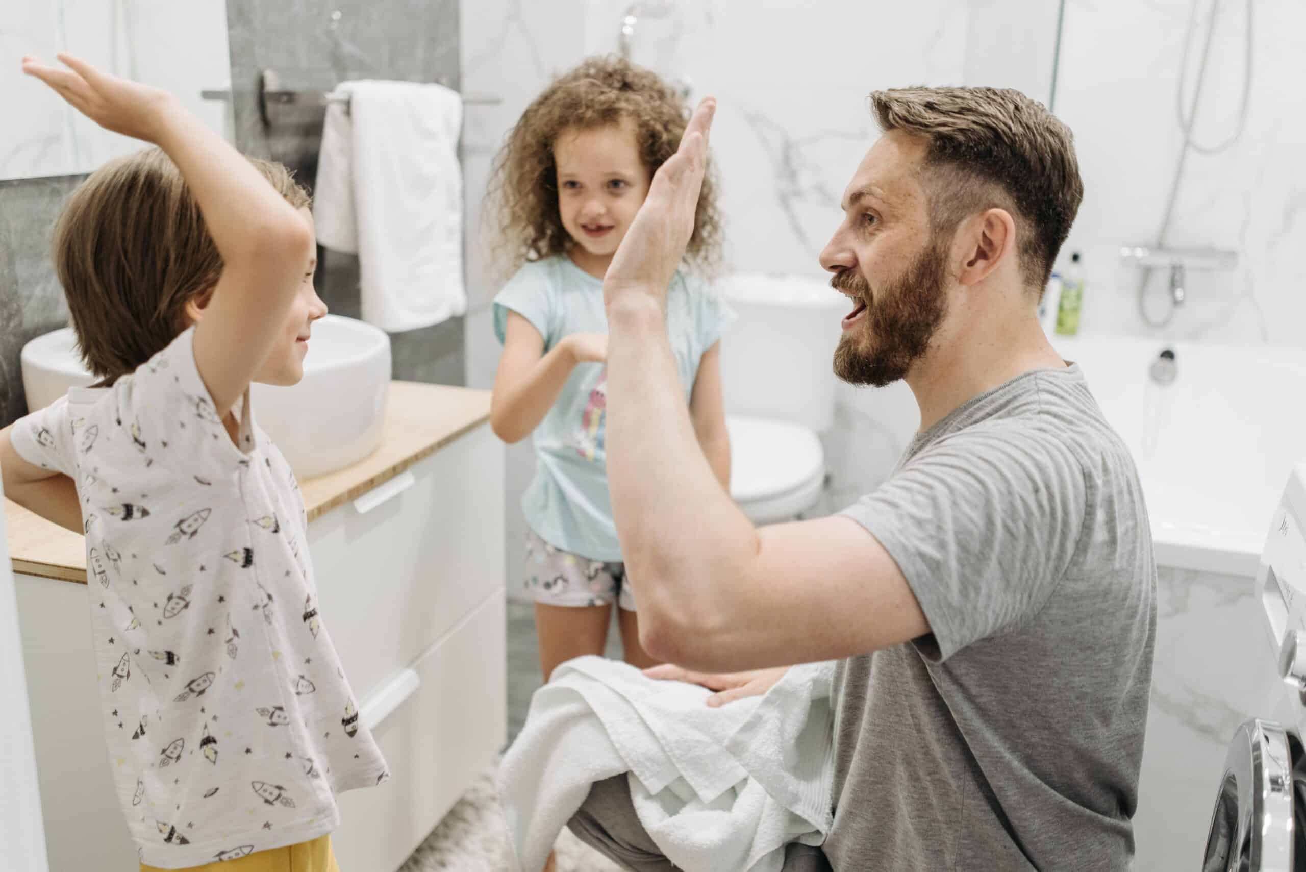 Child hand fiving dad in bathroom.