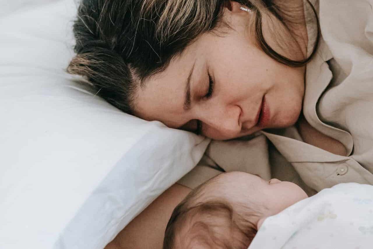 Mother sleeping with new born baby in bed.
