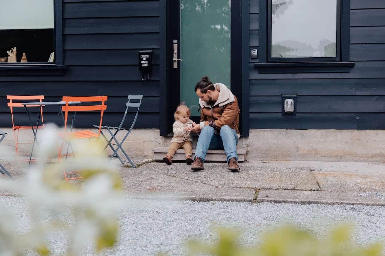 Father and child sitting near door in backyard.