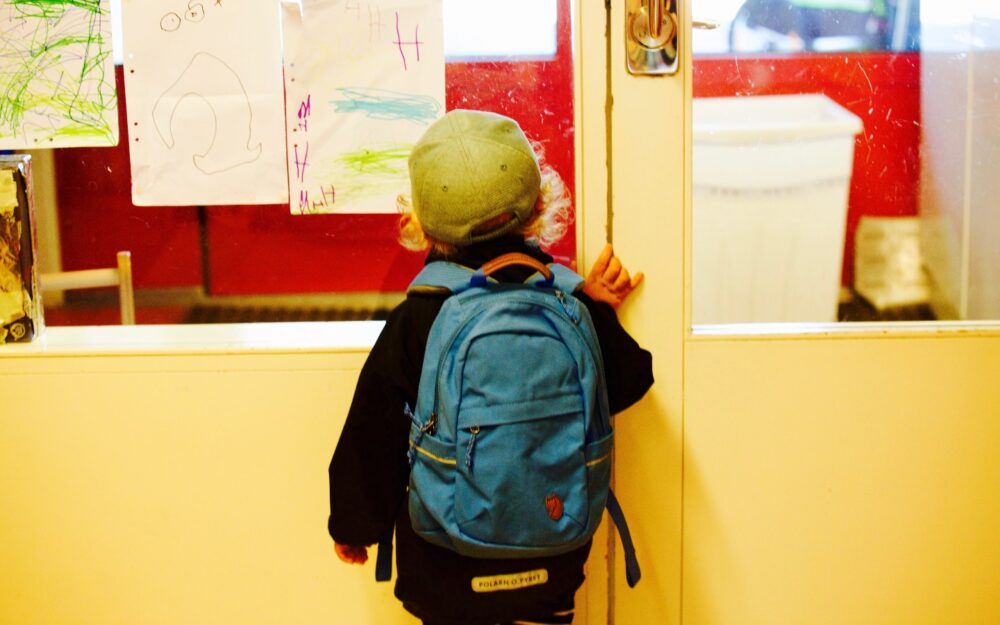 Child standing near school door entry.